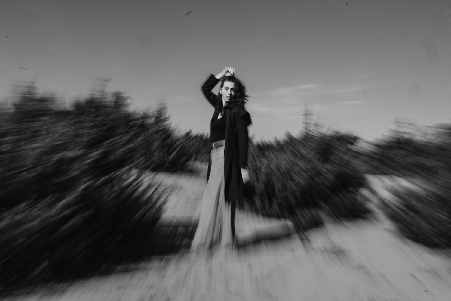 Artistic black and white photo showing a silhouette in motion against a blurred natural background.