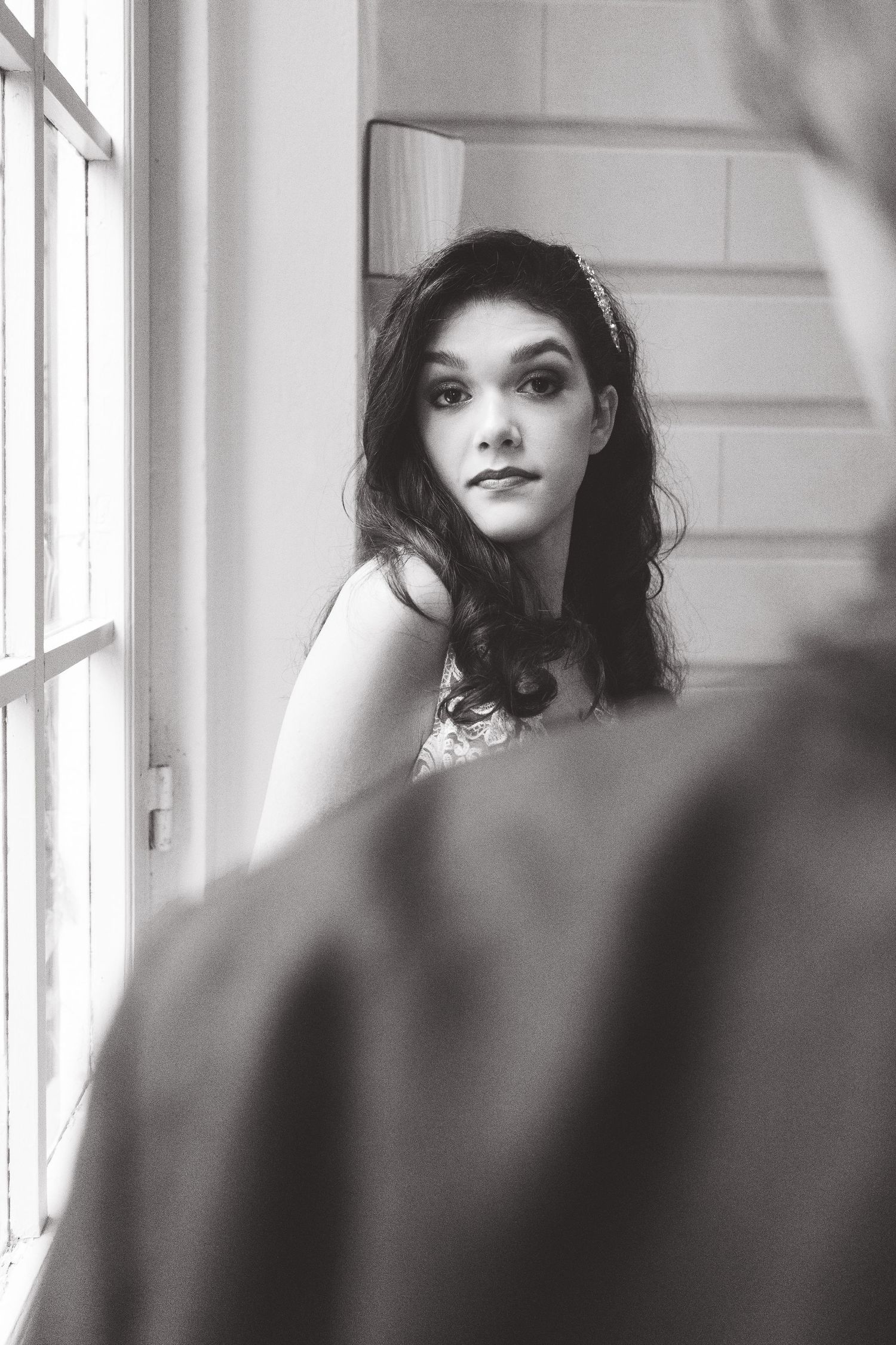 Dreamy black and white bridal portrait by a window with soft natural lighting.