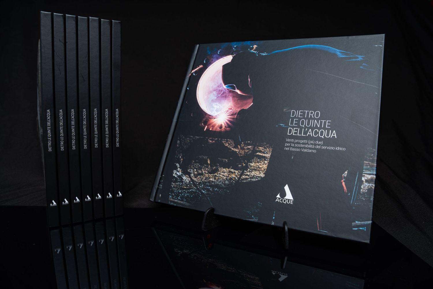 Modern book cover with blue abstract design displayed on black background with multiple books in the shadows.
