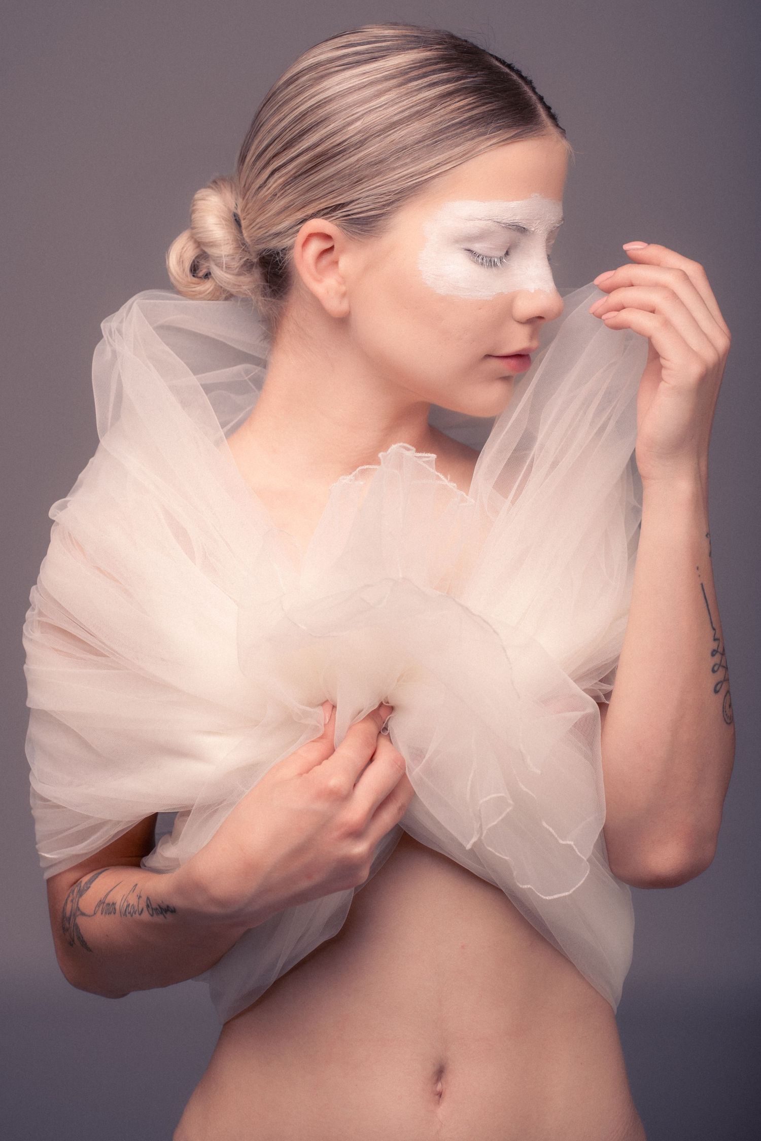 Artistic series showing a figure draped in flowing white tulle fabric against a dark background.