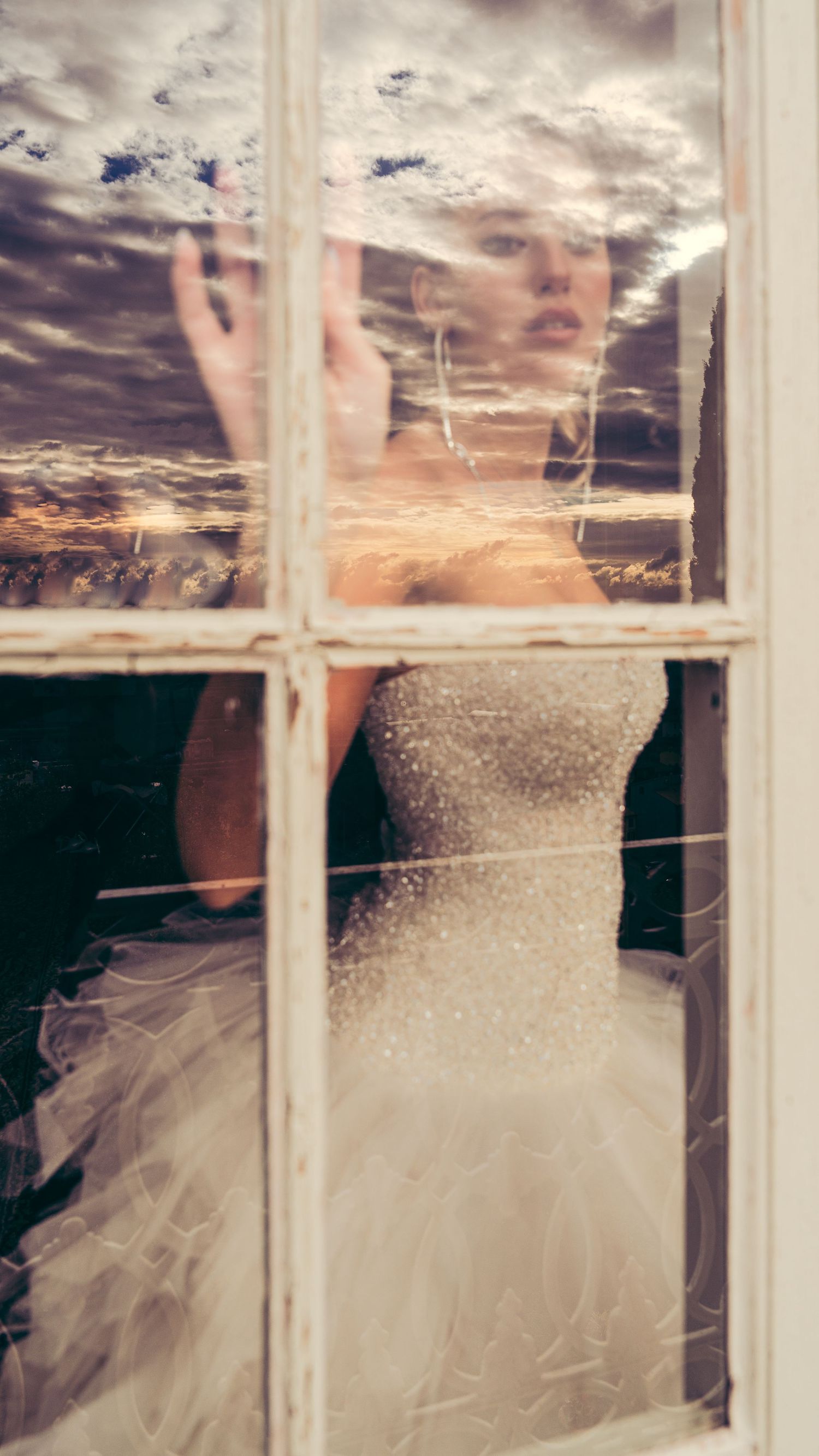 Intimate shot of the bride and groom exchanging vows behind a window in a warm sunset lighr