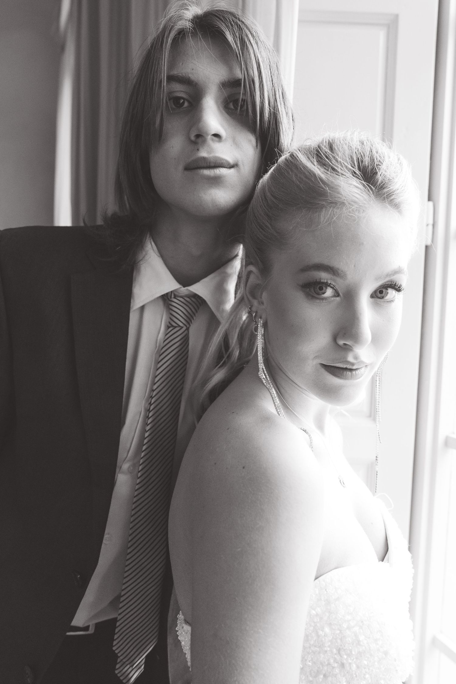 A black and white wedding portrait showing a couple posing together, with the bride in a strapless dress.