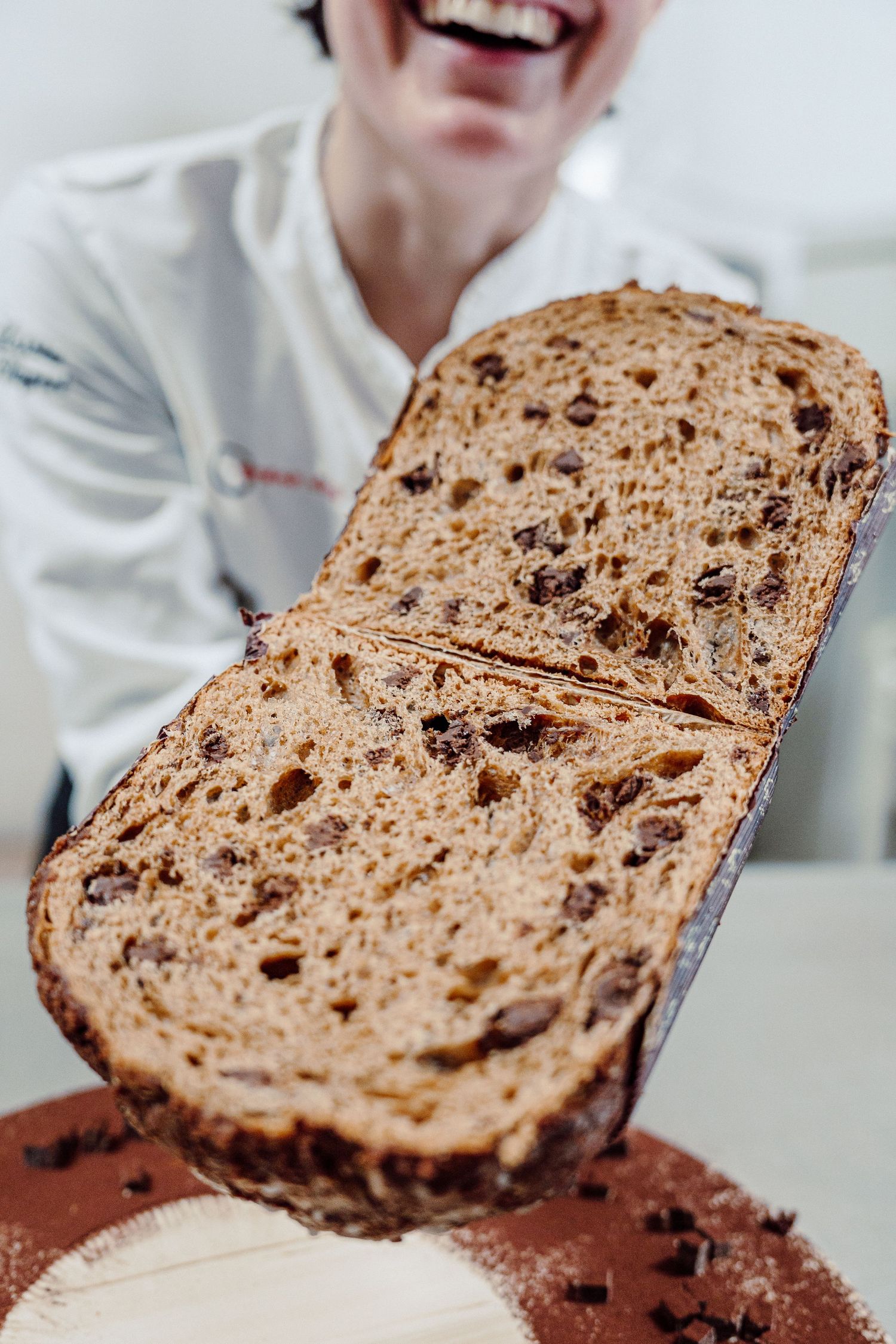 Freshly baked artisanal raisin bread loaf displayed on dark surface.