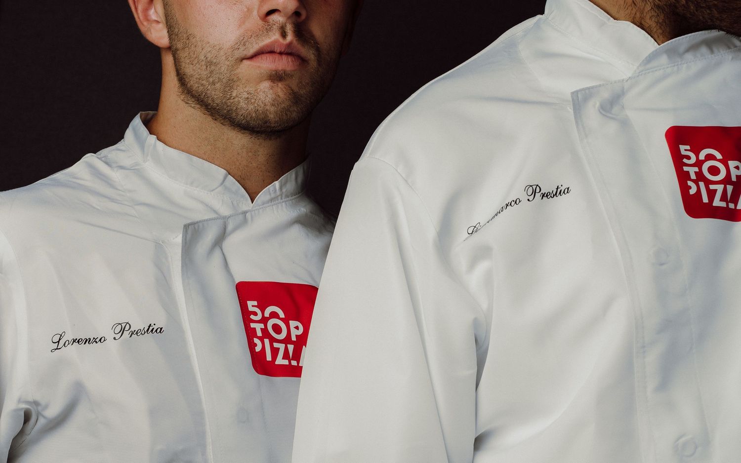 Close-up of white chef uniforms with red logo patches.