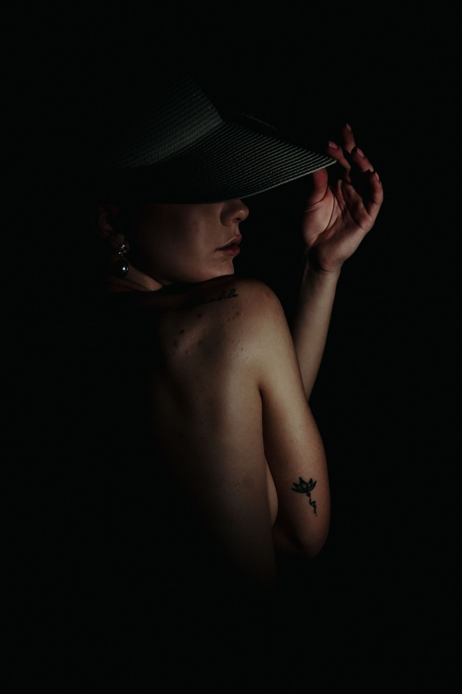 Dramatic low-key portrait with sun hat creating shadows and silhouettes.
