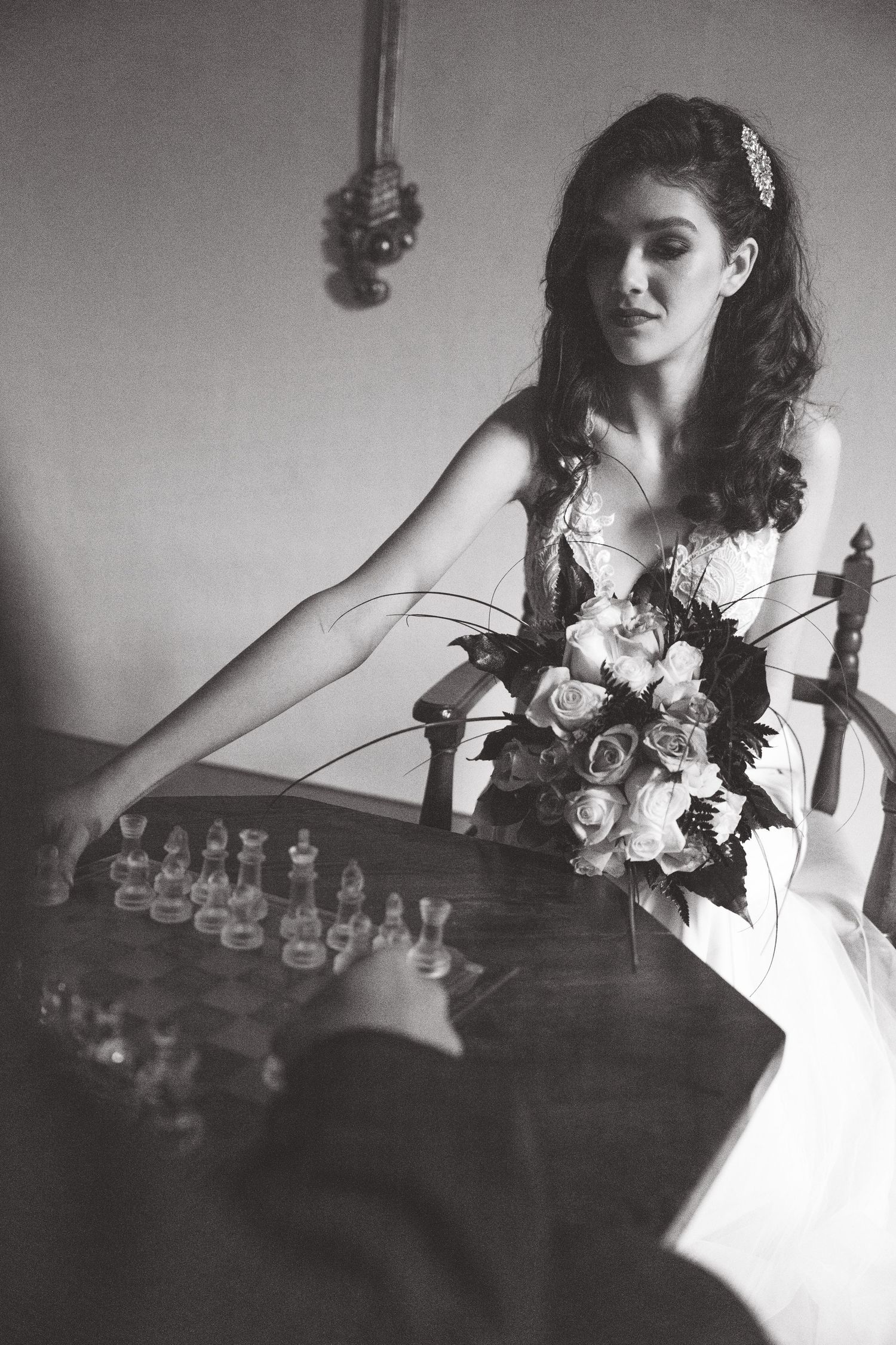 A dramatic black and white portrait series showing someone playing chess in formal attire with floral decorations.