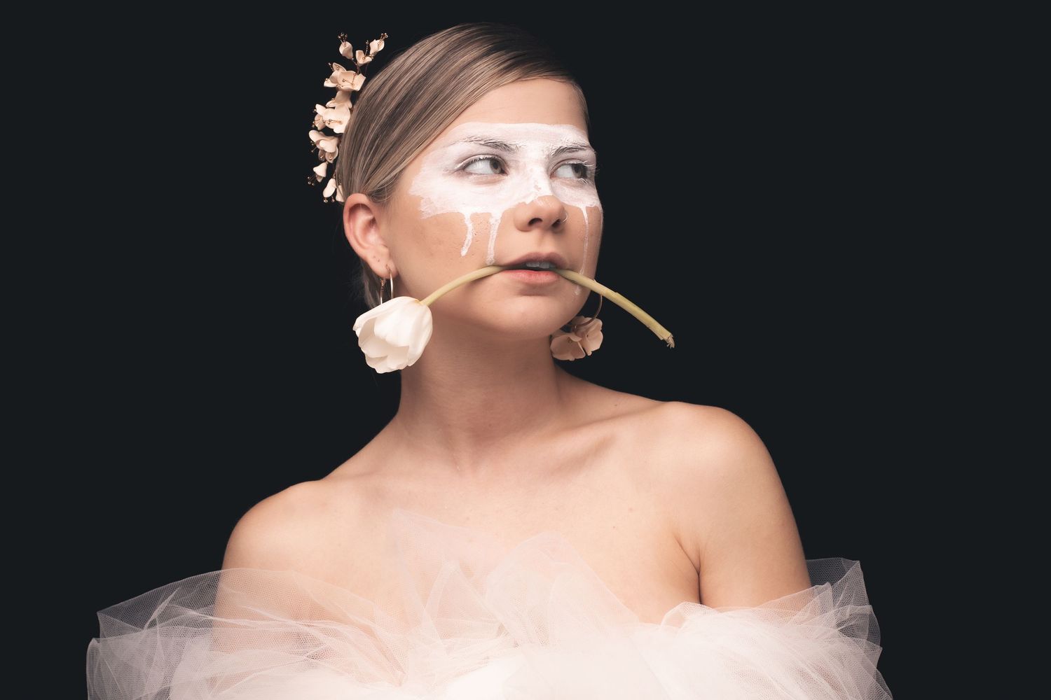 Delicate portrait series featuring floral accessories and soft tulle fabric against dark backdrop.