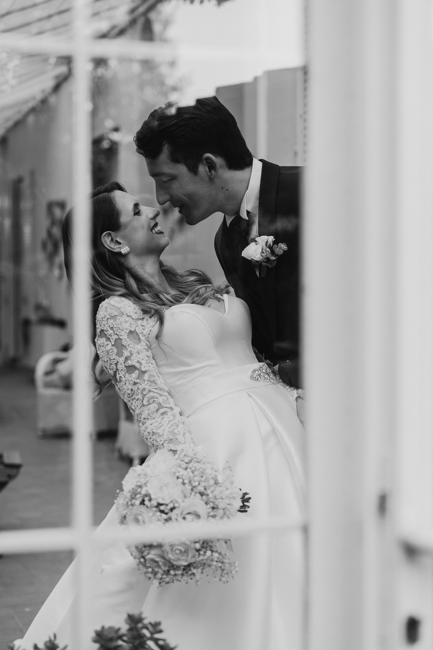 A romantic black and white wedding photo shows a couple embracing in a tender moment on their special day.