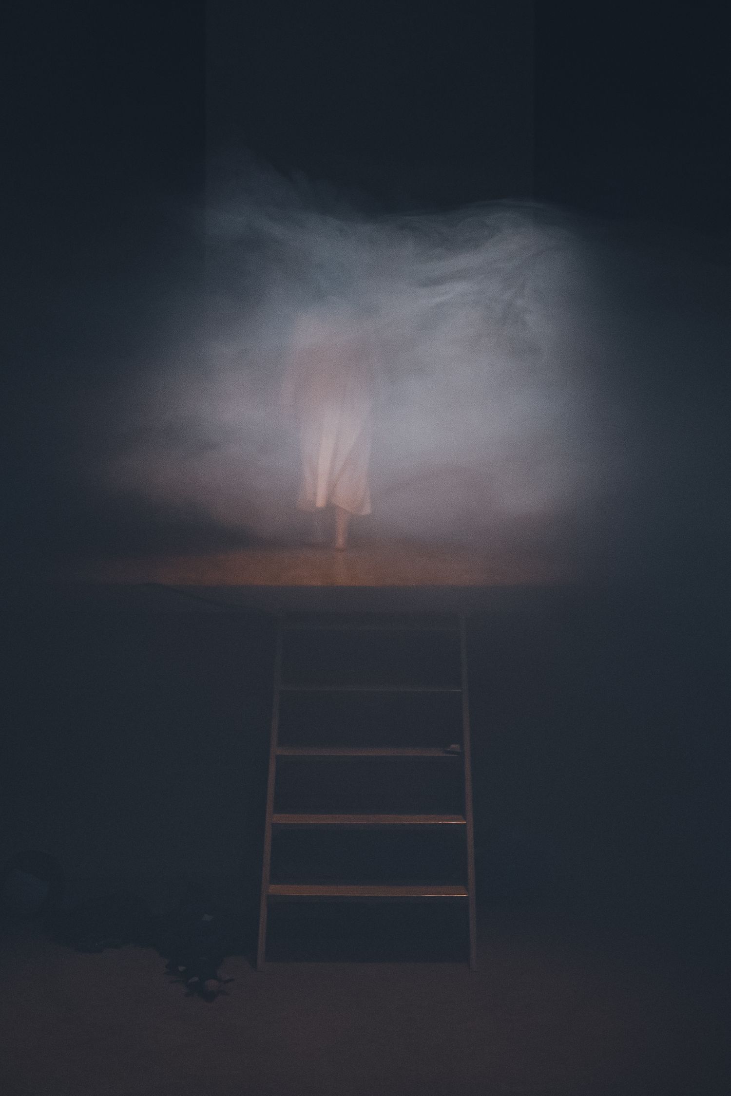 Mysterious wooden ladder leading into fog against dark background.