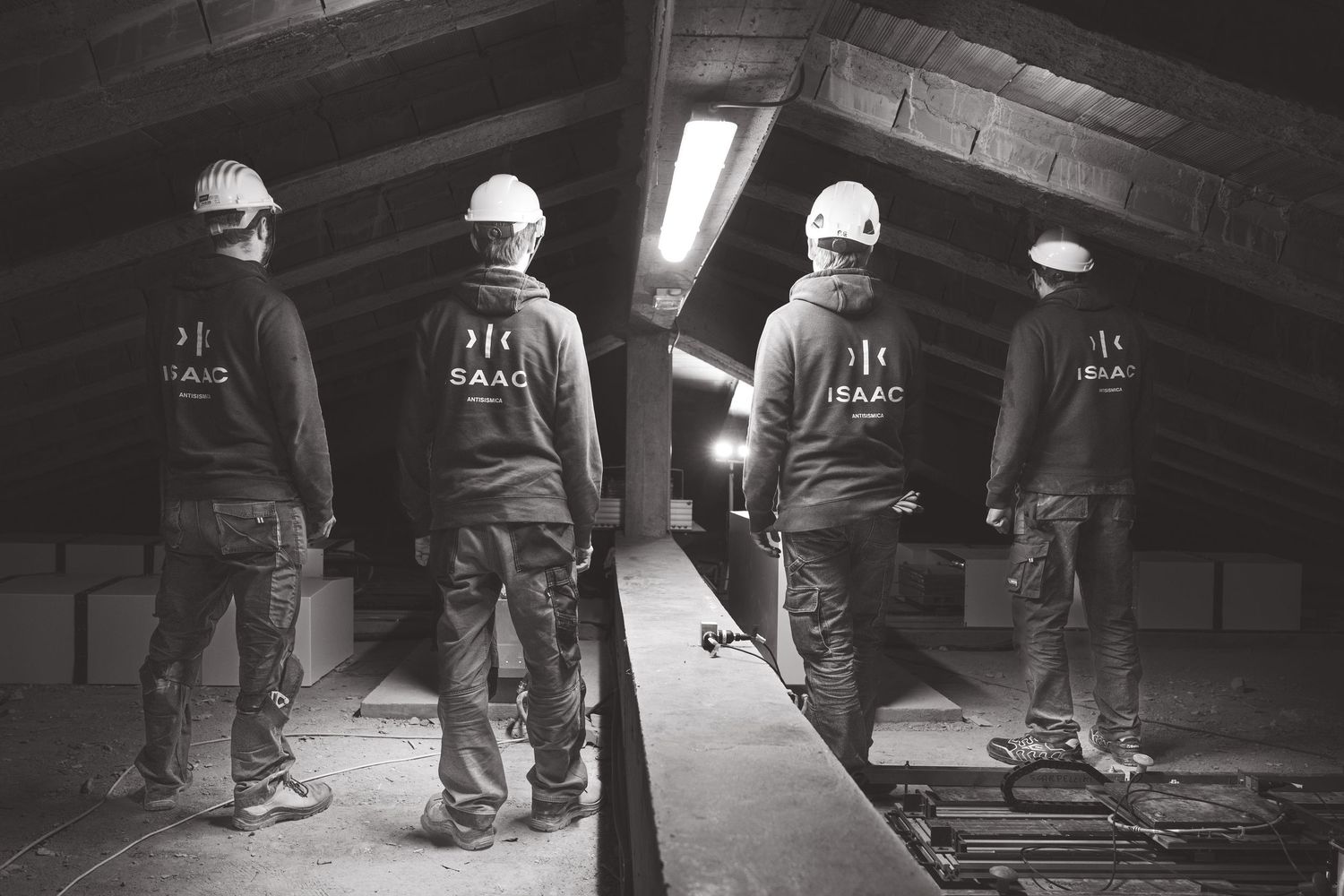 Four workers in hardhats and safety gear stand in a dark industrial hallway.