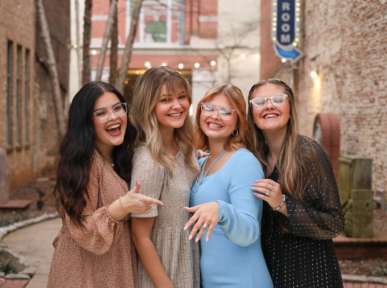 Friends celebrate and show off engagement ring in an urban alley.