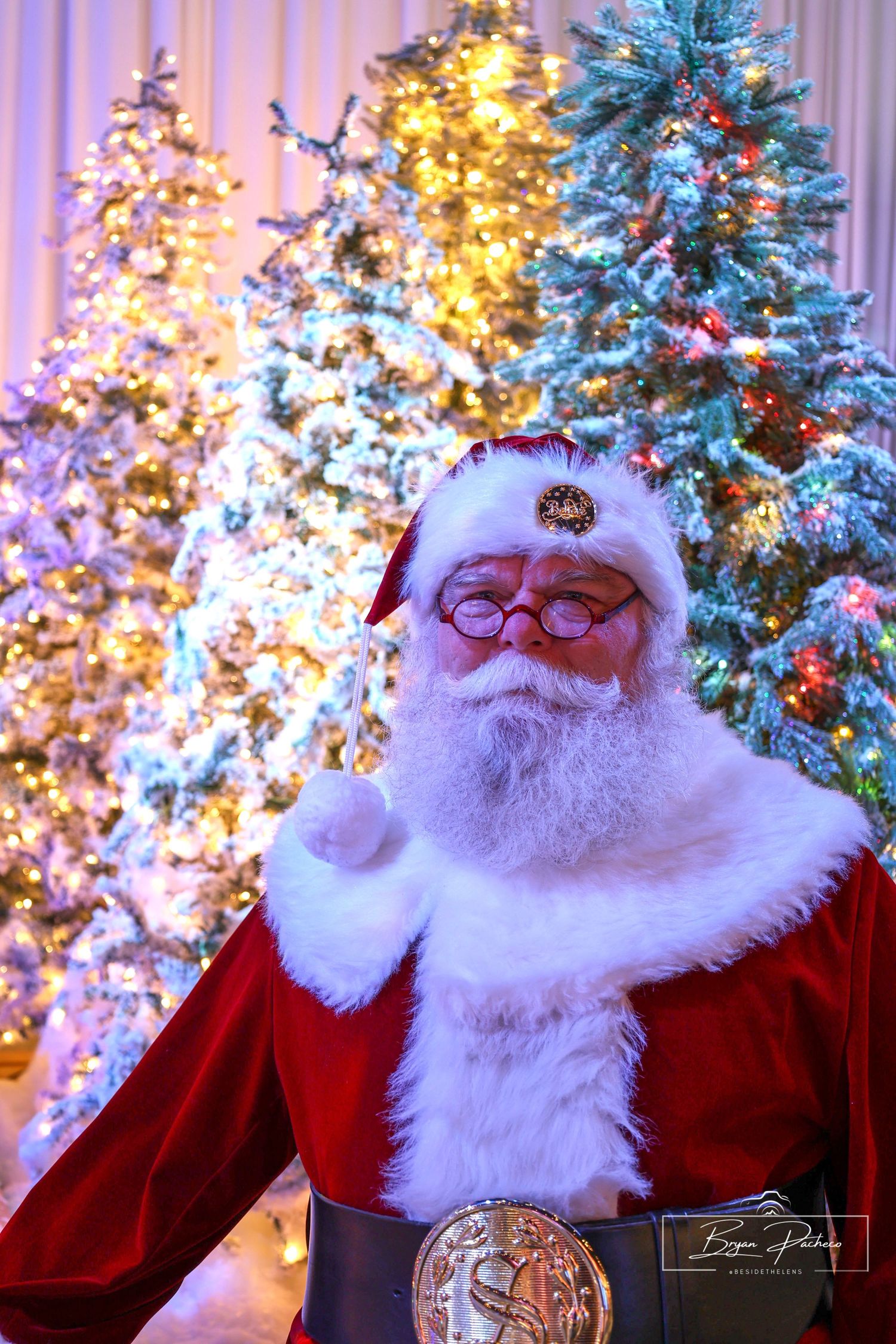 A festive holiday scene with decorated Christmas trees glowing with lights and a traditional red-suited Santa figure.