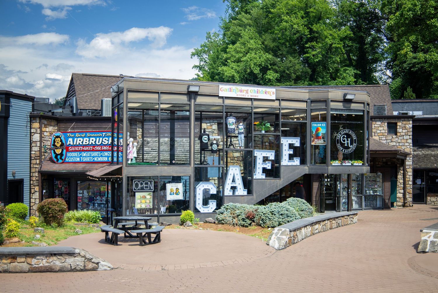 Exterior view of a cafe building with large 'CAFE' lettering on the storefront under blue sky.