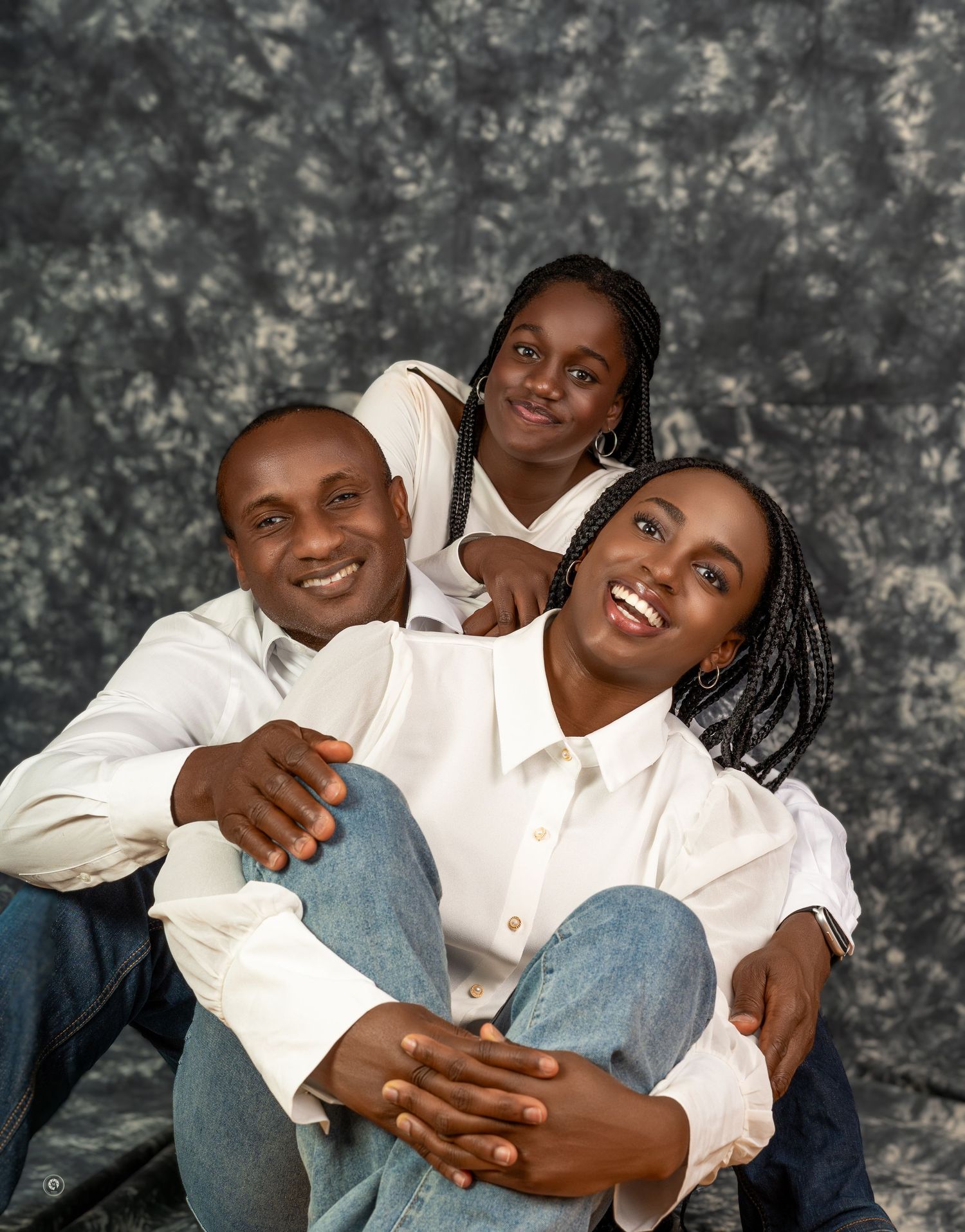 A family wearing white shirts poses together in a series of candid black and white portraits showing playful interactions.