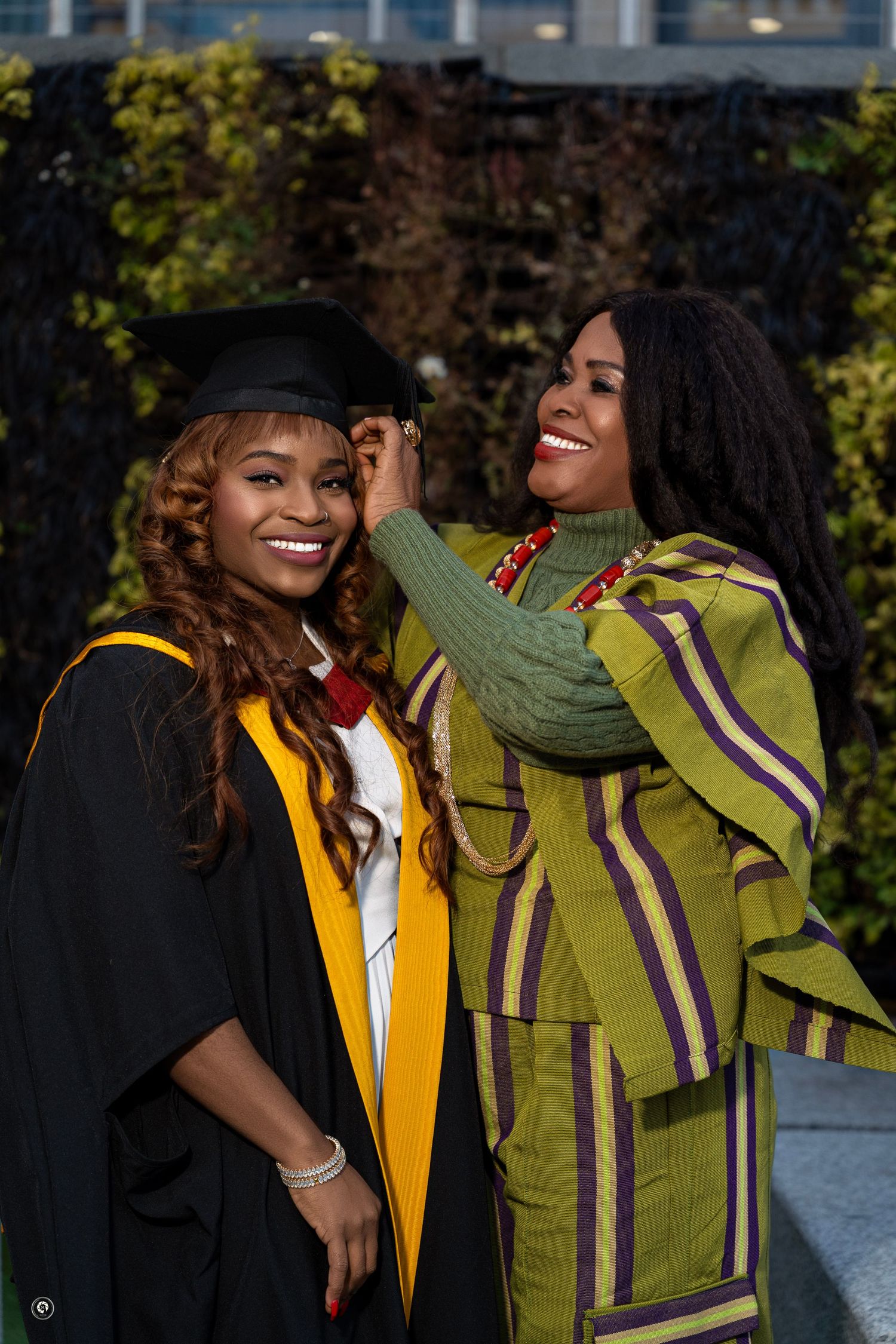 Two graduates in academic regalia share joyful moments during a graduation celebration outdoors.