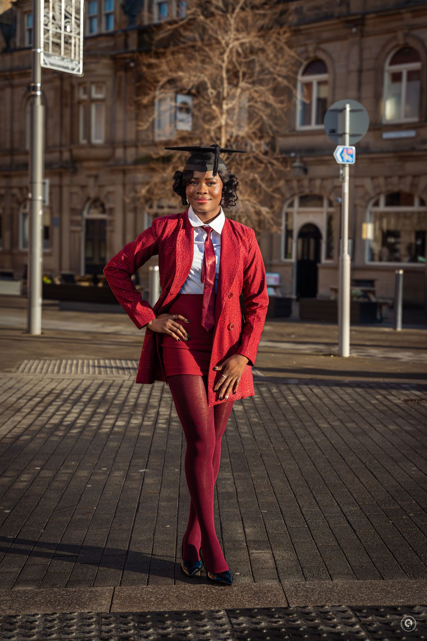 A sequence of four photos showing a person in a stylish burgundy suit striking dynamic poses on a cobblestone plaza.