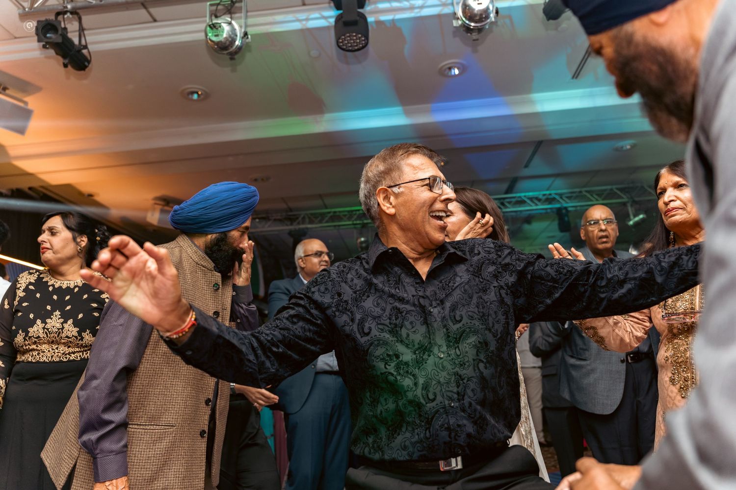 People dancing and celebrating at a lively indoor party with colorful lighting and festive atmosphere.