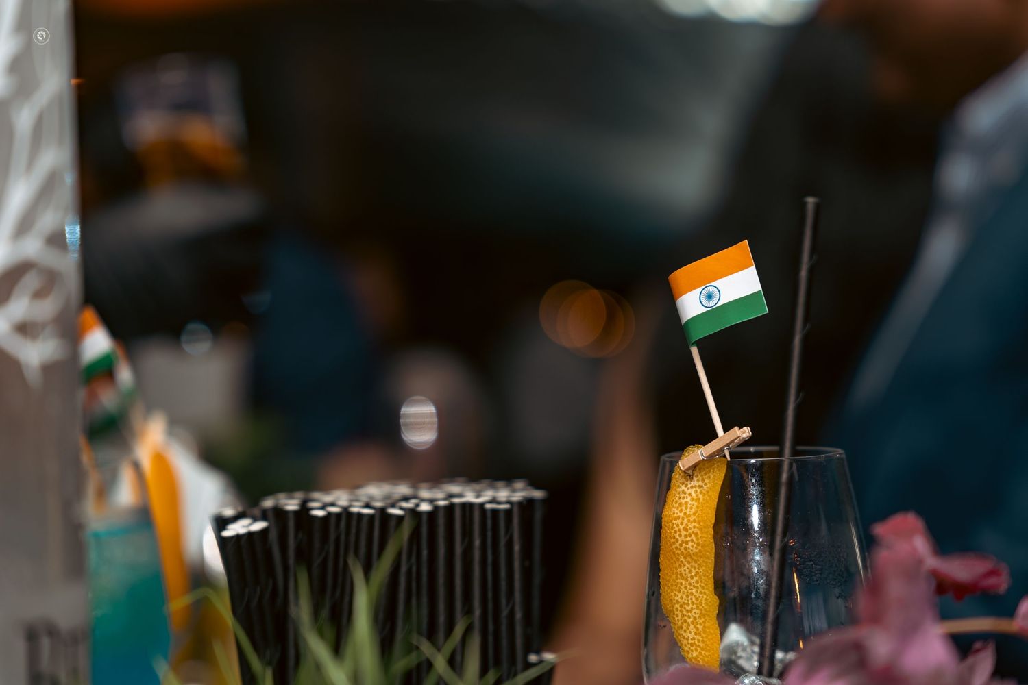 Colorful cocktails with fresh fruit garnishes lined up at a bar in dim lighting.