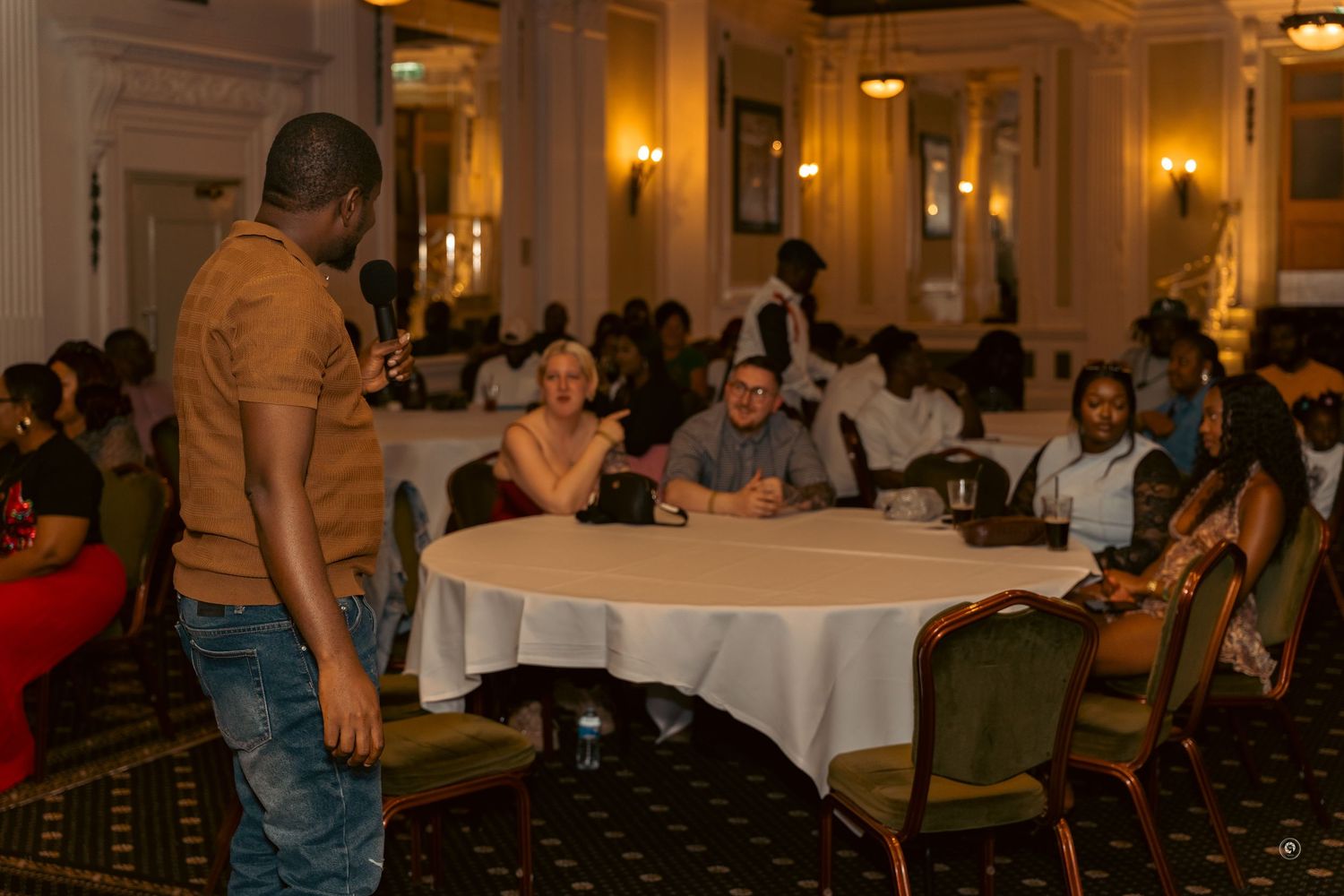 Diners seated at round tables in an elegant ballroom with warm lighting and ornate decor during an evening event.