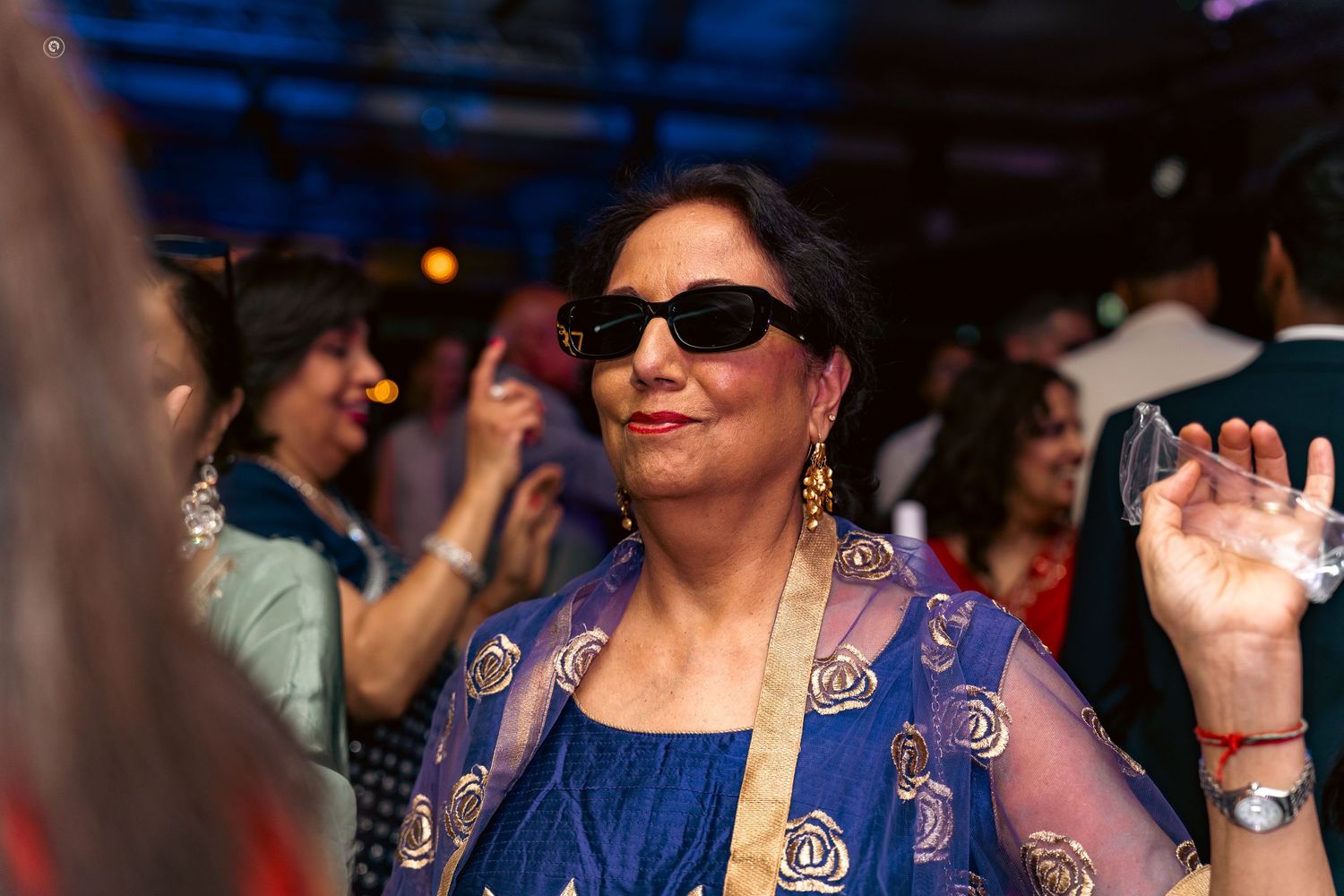 A crowd of people in blue outfits dance and celebrate at what appears to be a festive gathering or party.