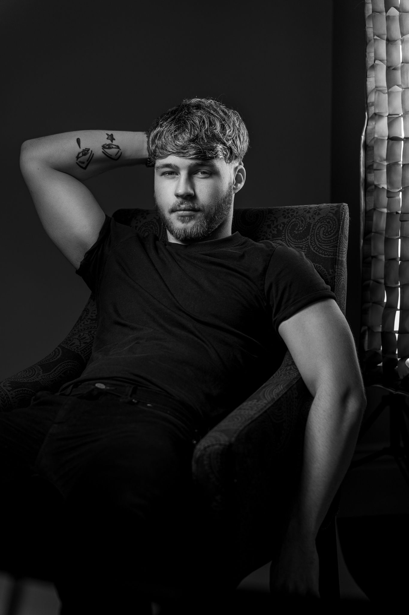 Moody black and white photo series depicting a figure reclining in dramatic shadows on a chair.