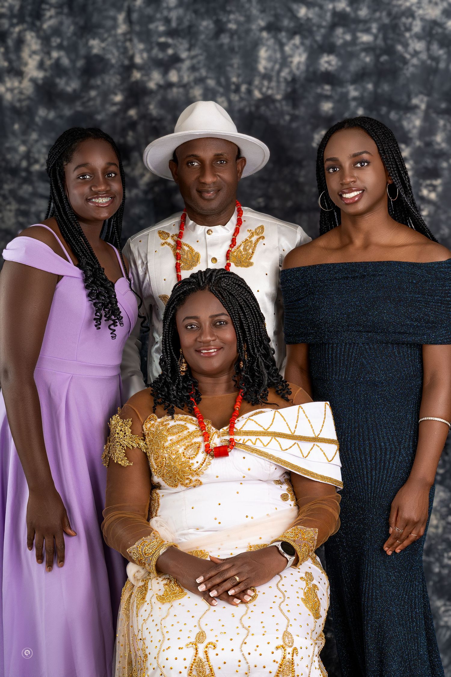 A group photo showing people wearing elegant purple, black and gold formal attire against a dark backdrop.