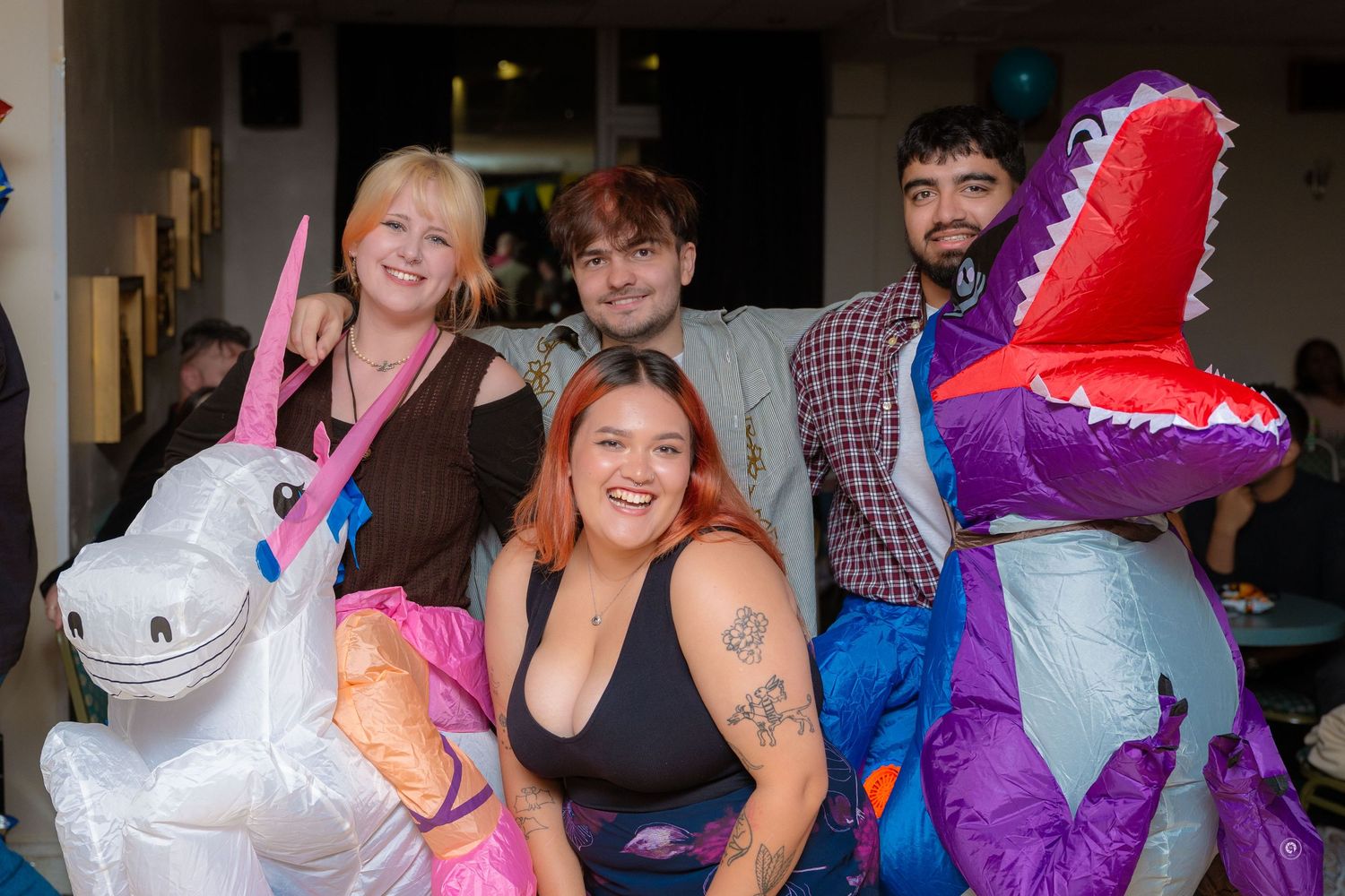 People celebrating at a party with colorful balloon decorations and festive atmosphere.
