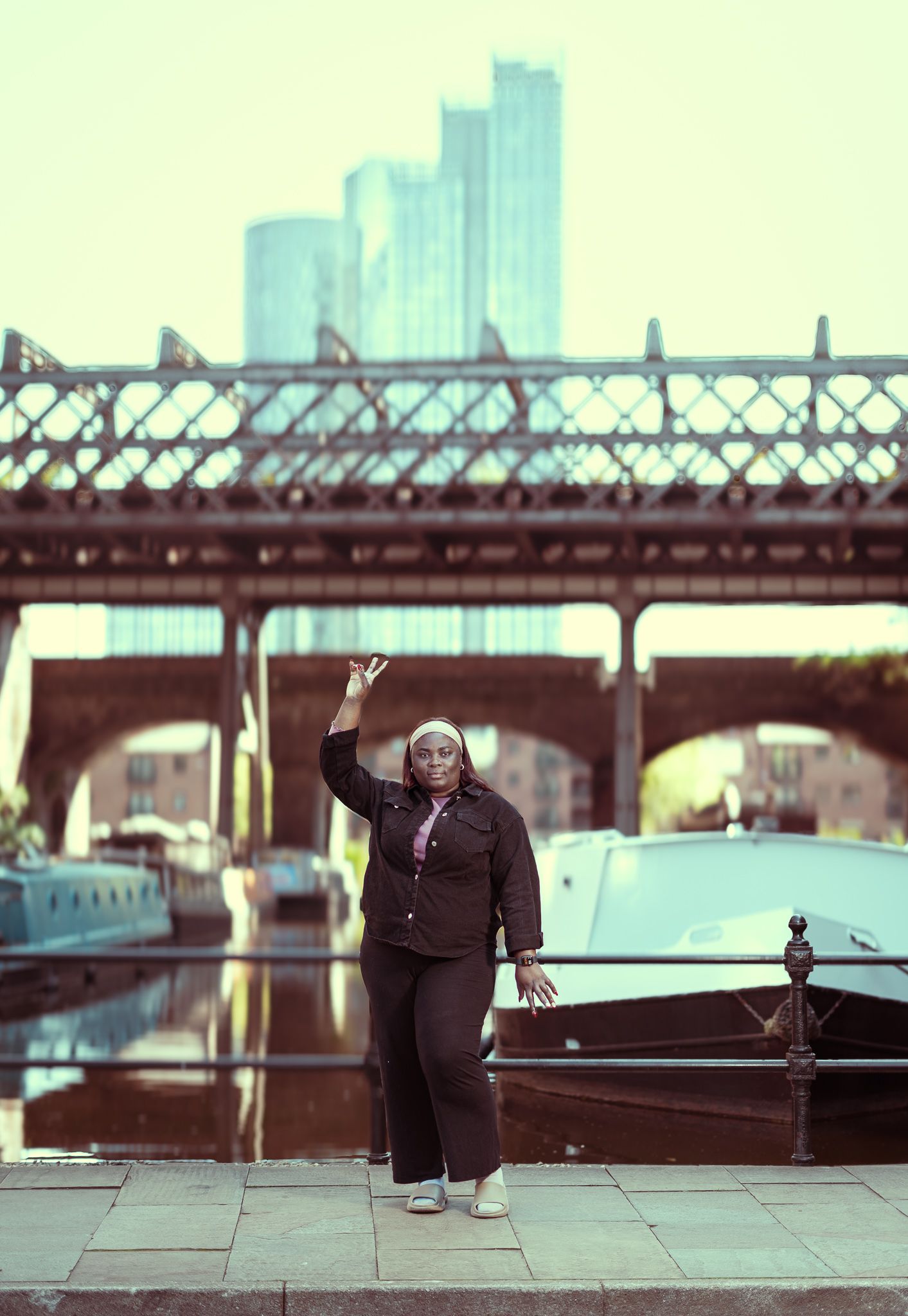 A sidewalk view of a pedestrian bridge in an urban area with a city skyline in soft focus background.