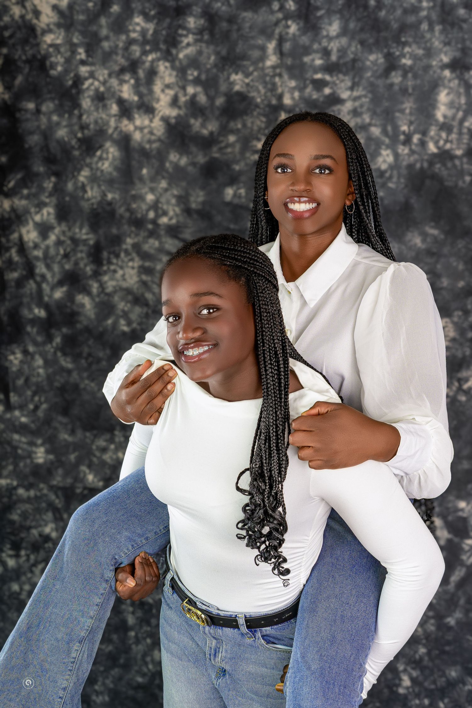 A person in a white sweater and jeans poses playfully against a dark textured backdrop in a photo series.