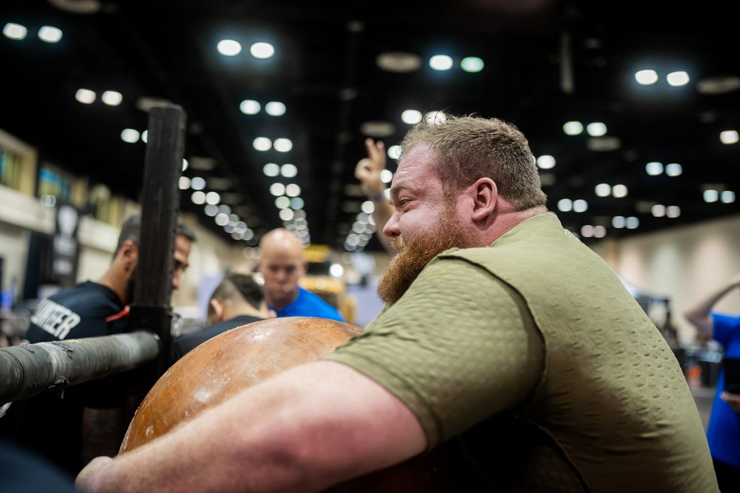 Athletes intensely competing during a strength competition in a large convention center.