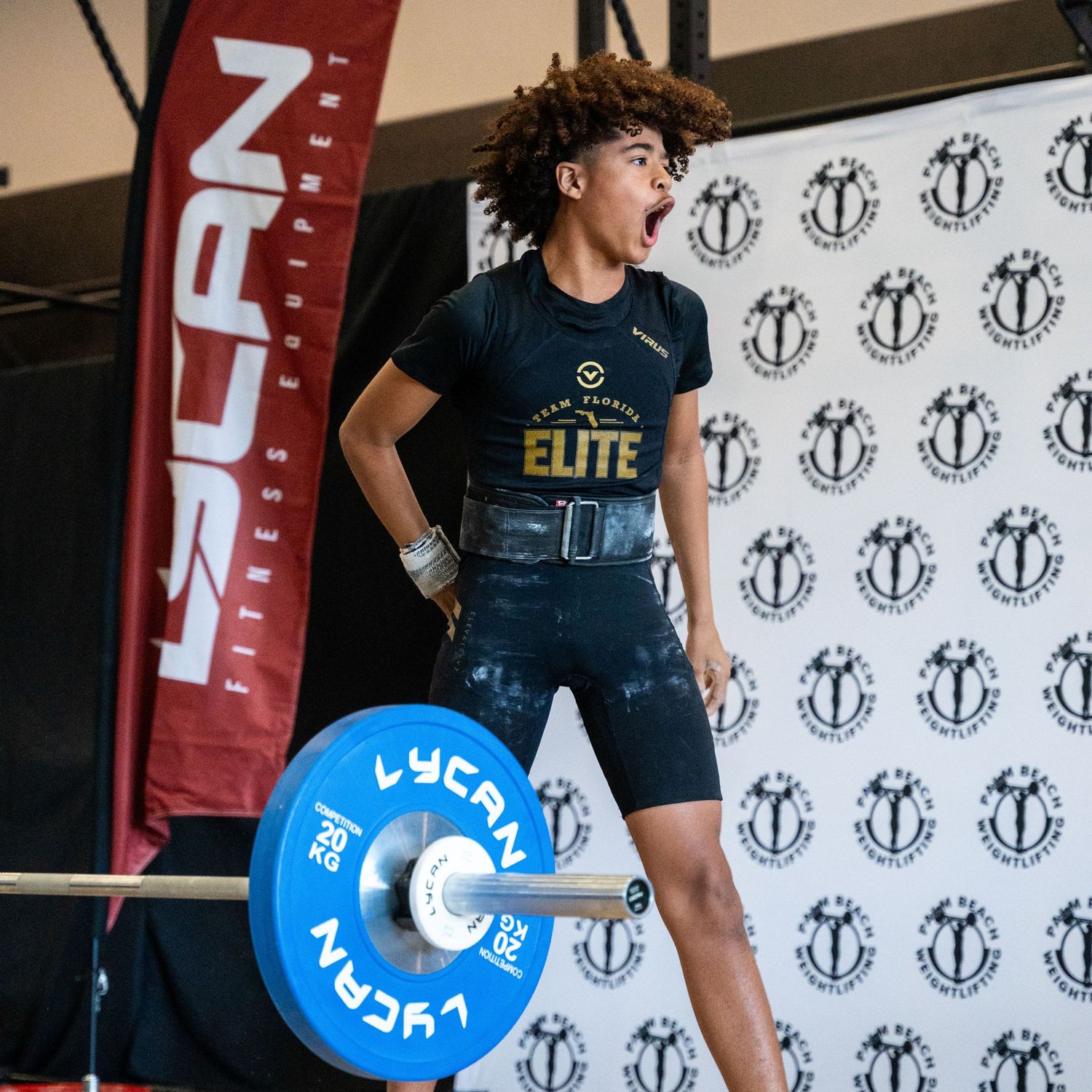 Young athlete in competition attire poses with Lycan weightlifting plates.