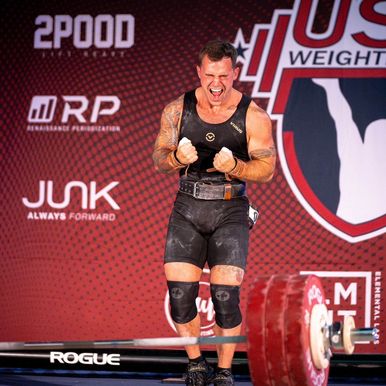 Competitive weightlifter performs at USPF competition with Rogue equipment and red backdrop.