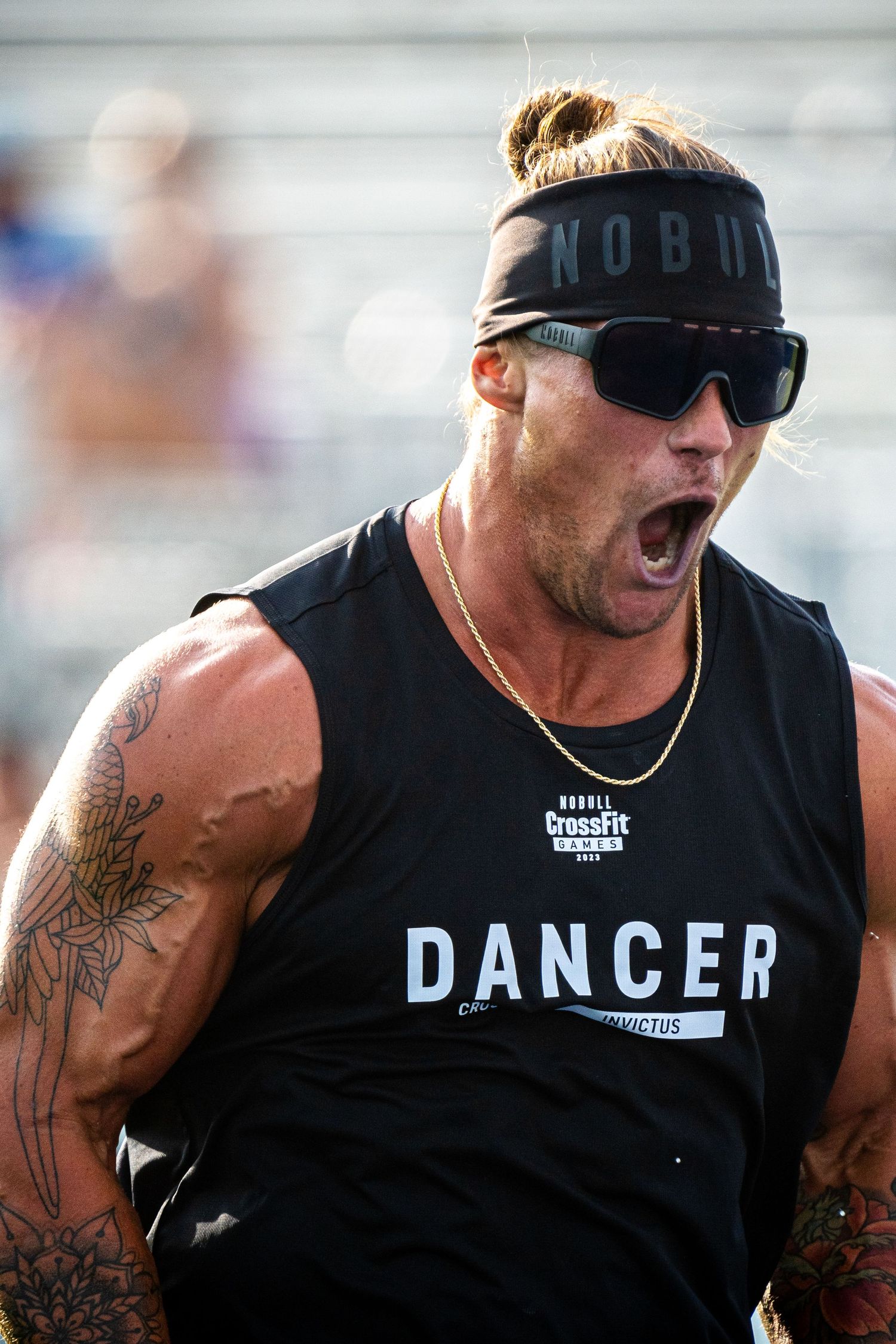 Athletic person in a tank top with DANGER text and sunglasses shouting energetically.