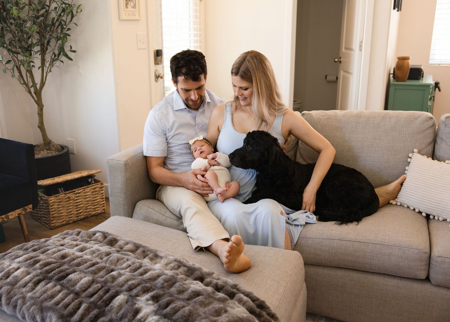 In-home newborn lifestyle photography in Utah — parents kissing baby during cozy family session