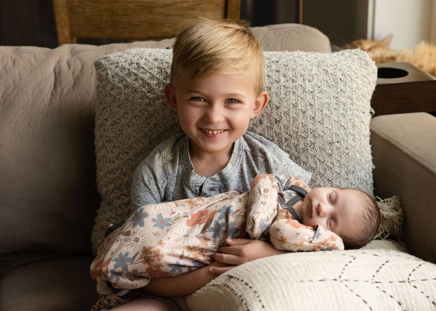 Sibling cuddling newborn baby during at-home lifestyle session in Salt Lake City, Utah