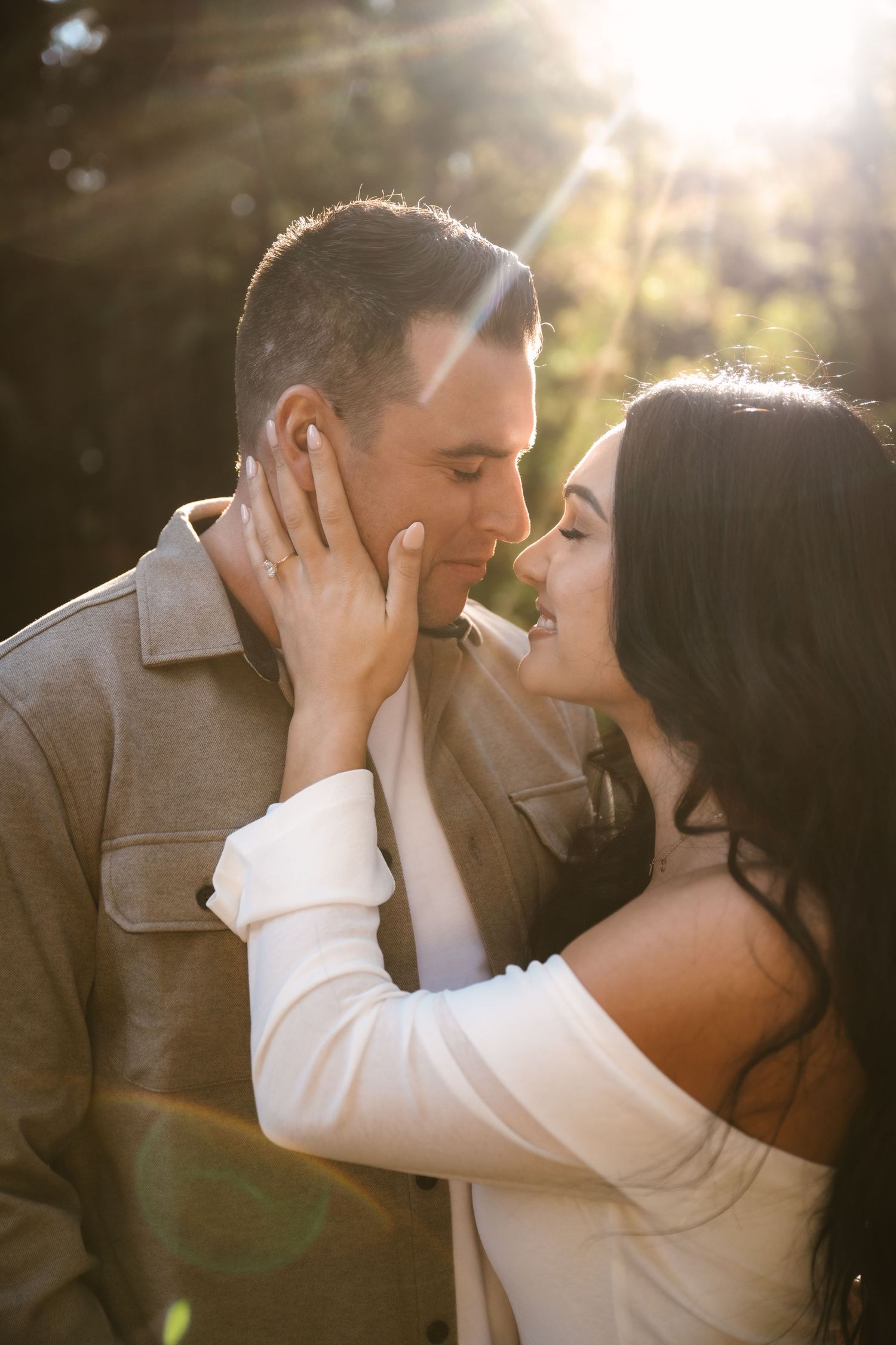 A romantic couple sharing tender moments in golden sunlight during a photo session.