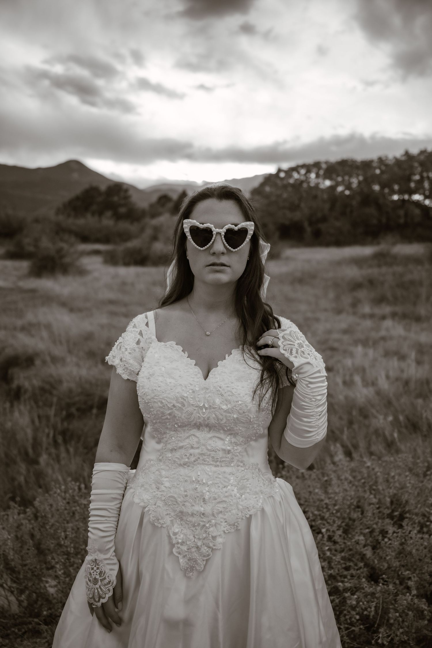 Retro-styled bridal portrait with cat-eye sunglasses against mountain backdrop.