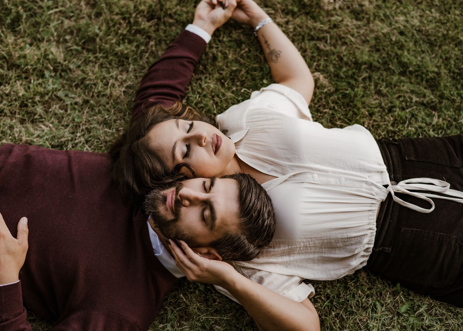 Couple lying together on grass in intimate outdoor portrait.