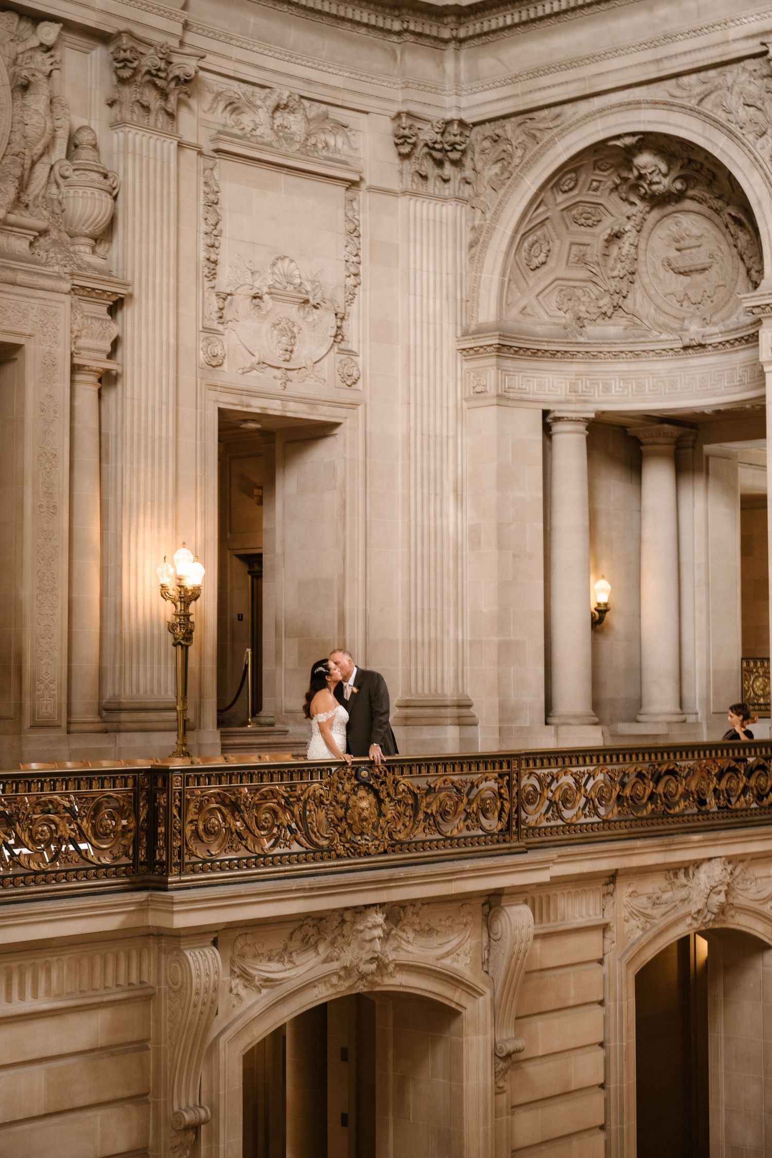 A romantic moment captured on an elegant marble balcony with ornate architectural details.