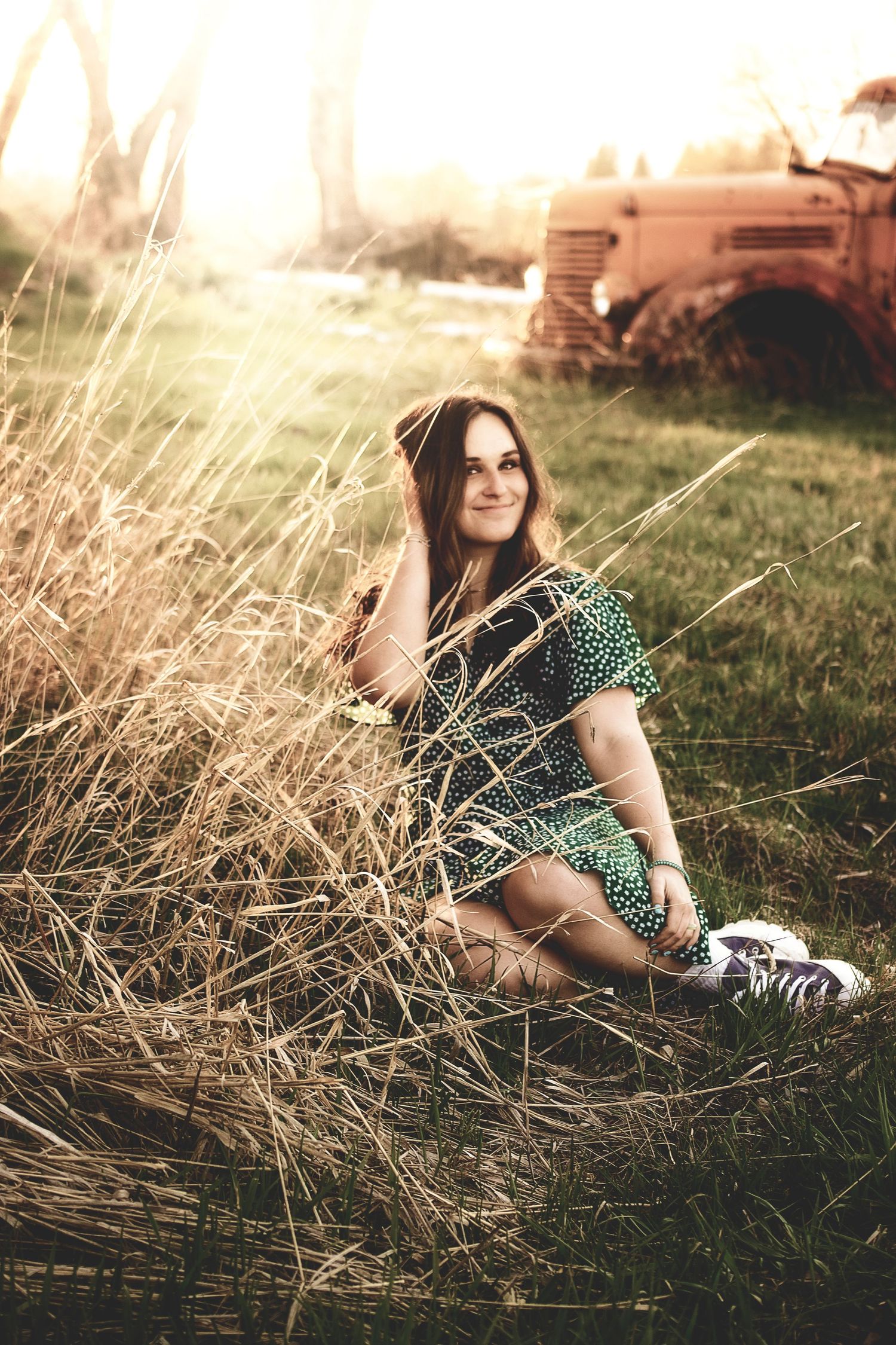 Artistic portrait in tall grass during golden hour wearing polka dot dress.