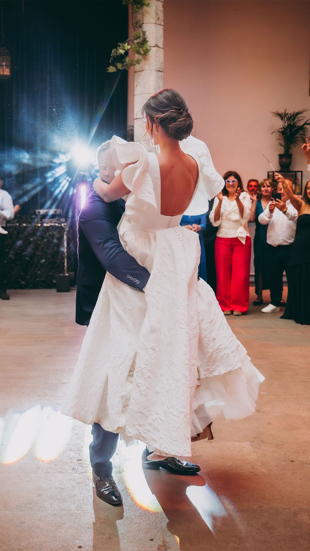 Primer baile de novios en el Palacio de Moutas, Asturias. Novio sostiene a la novia en brazos con los invitados al fondo.