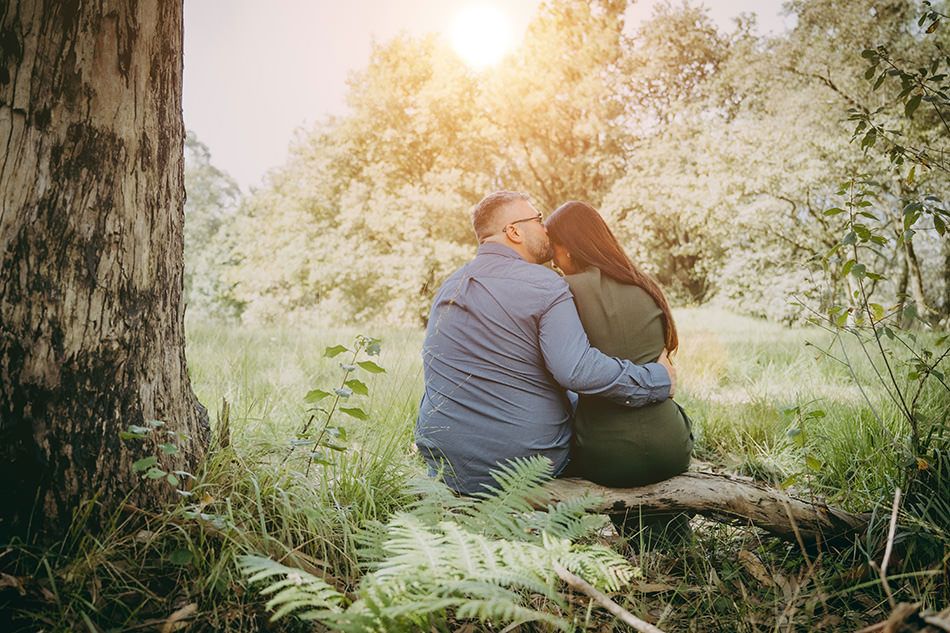 Novios se abrazan en una sesión de pre boda en Gijón. De fondo el bosque y un sol que deja una bonita contra luz.