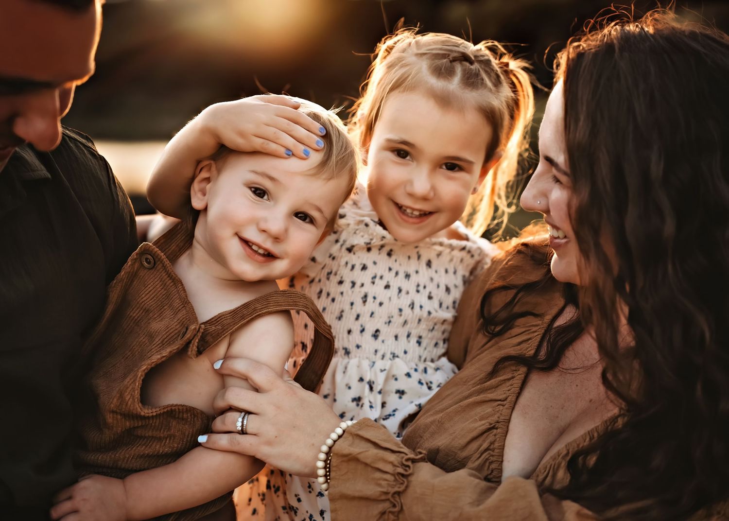 A warm sunset photo of a family enjoying a tender moment together outdoors.