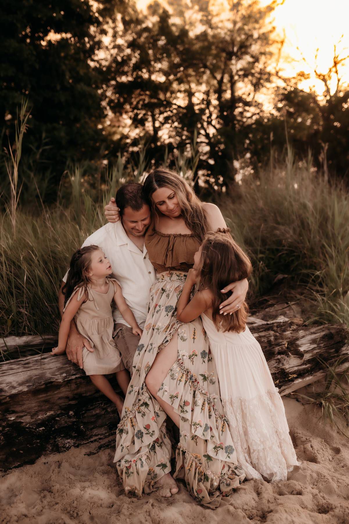 Family enjoying a tender moment together on sandy beach at sunset.