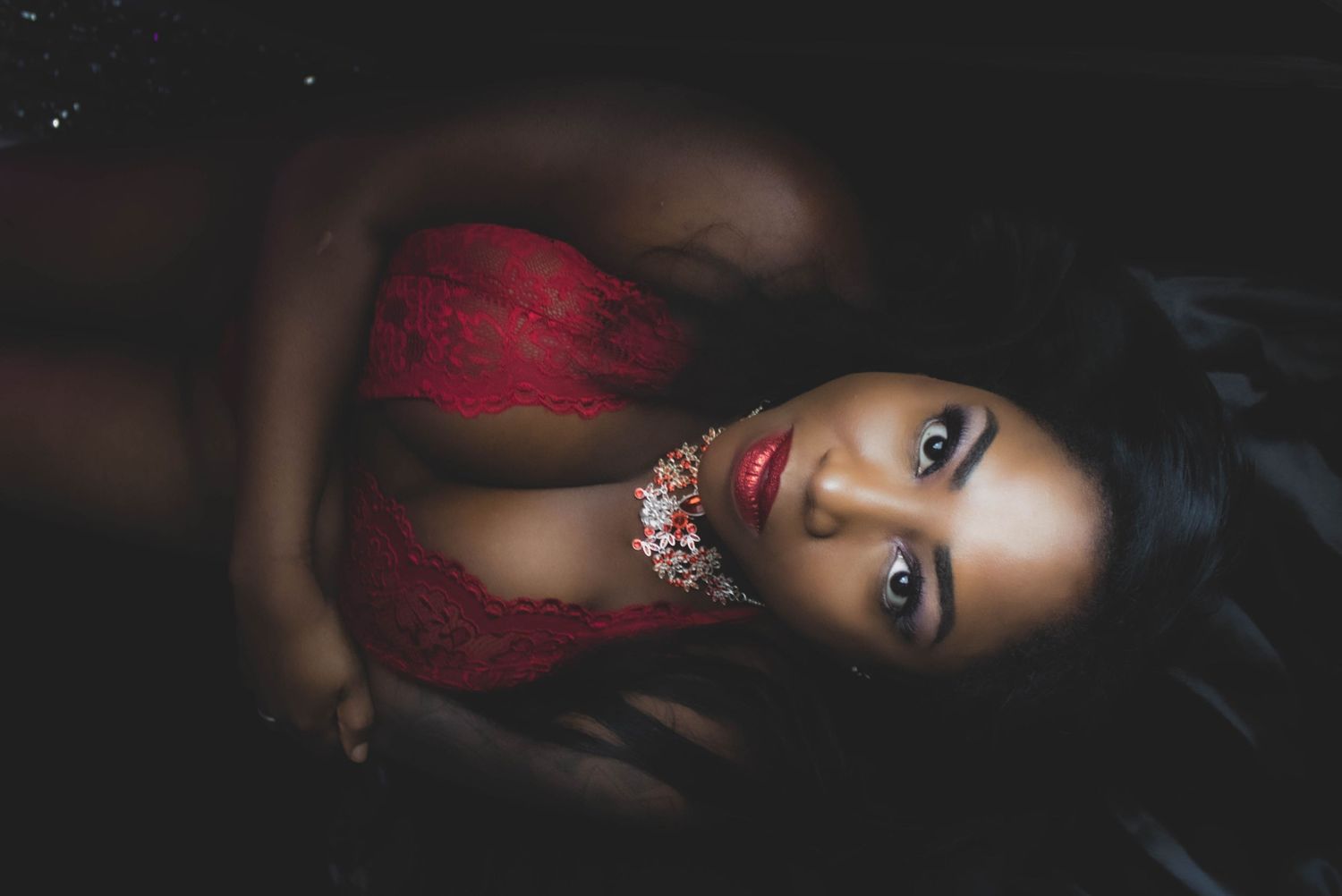 Dark atmospheric portrait showing red dress and dramatic lighting effects.