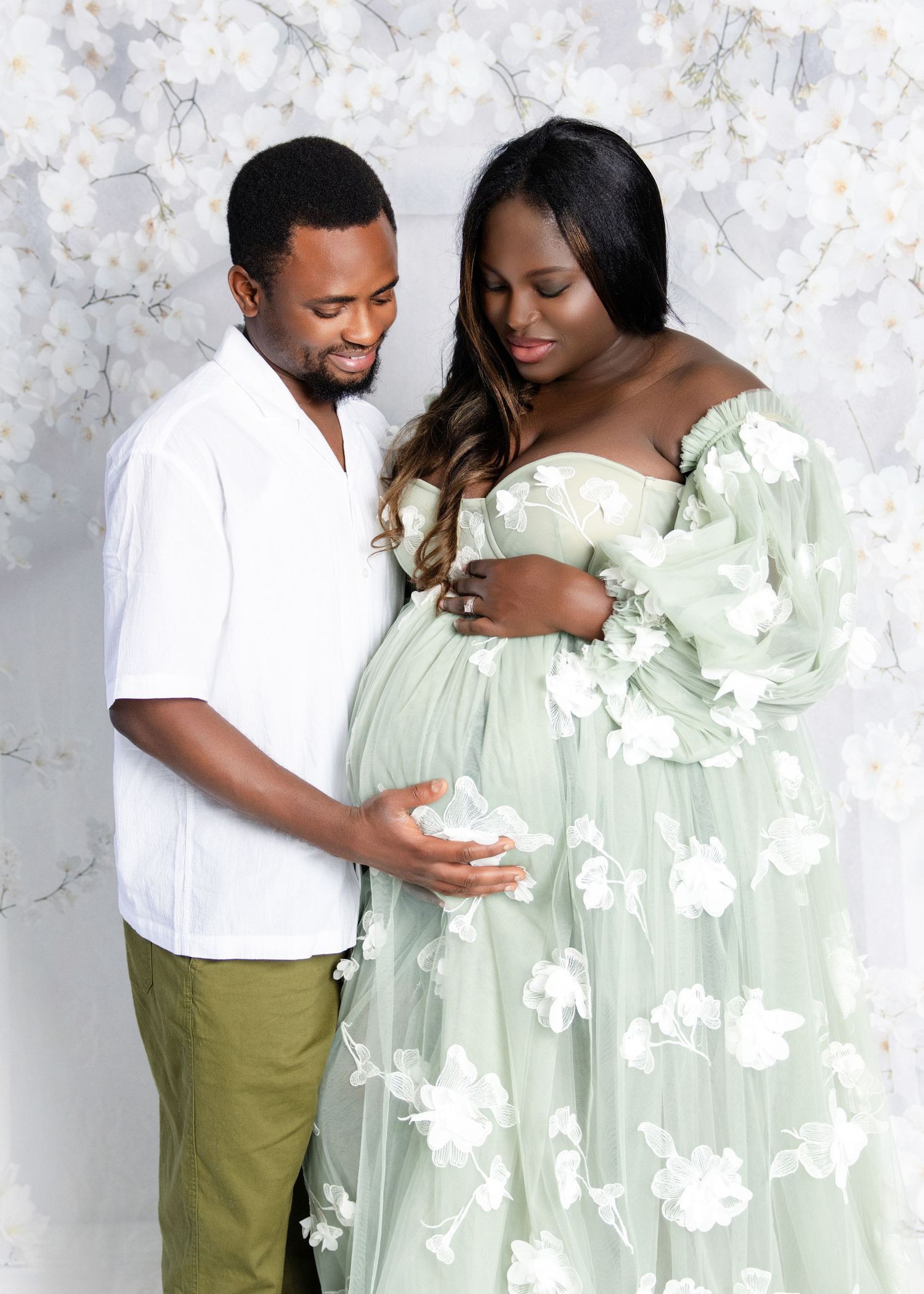 Couple sharing tender moment with husband gently touching pregnant wife's baby bump.