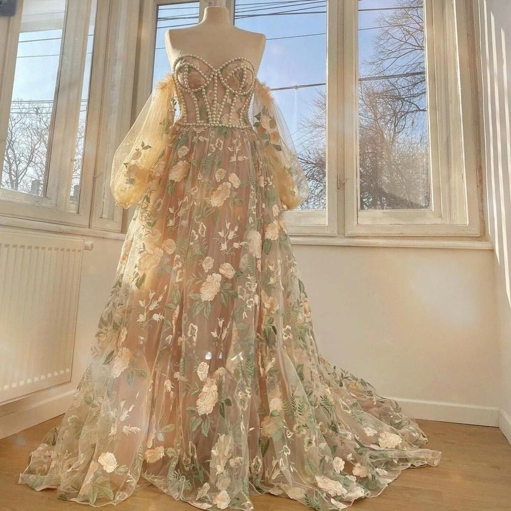 Elegant floral embroidered tulle ball gown with puff sleeves and sweetheart neckline displayed on mannequin near window.
