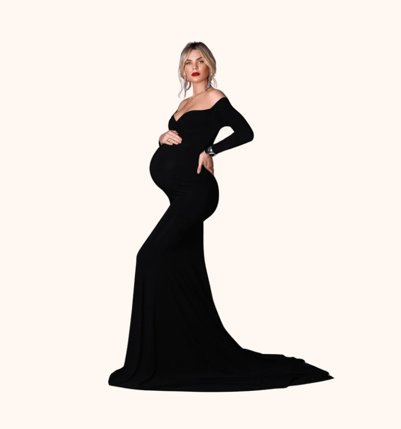 Pregnant woman wearing an elegant black off-shoulder mermaid maternity gown with long sleeves and a flowing train.