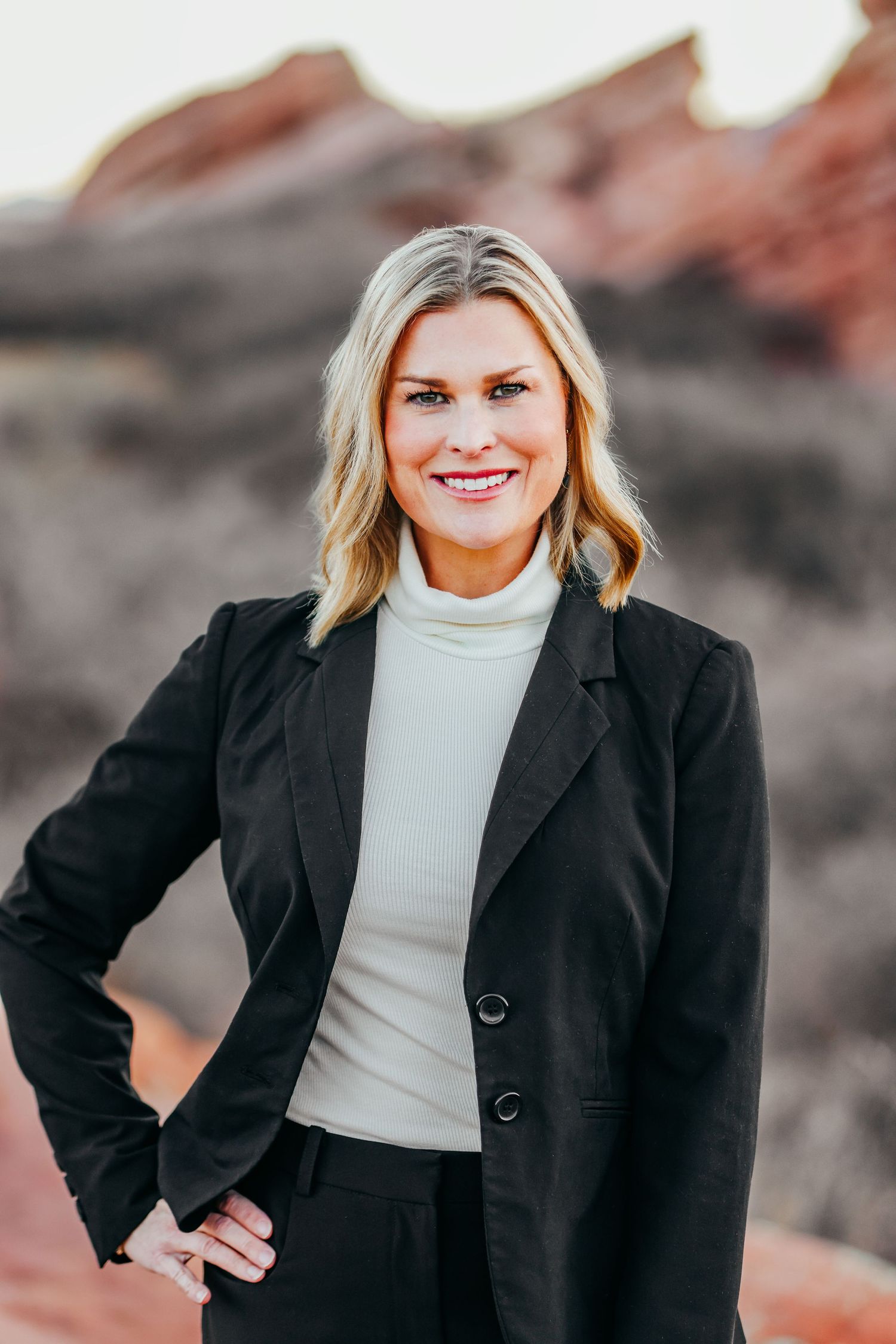 Professional outdoor portrait in business attire against dramatic desert rock formations.