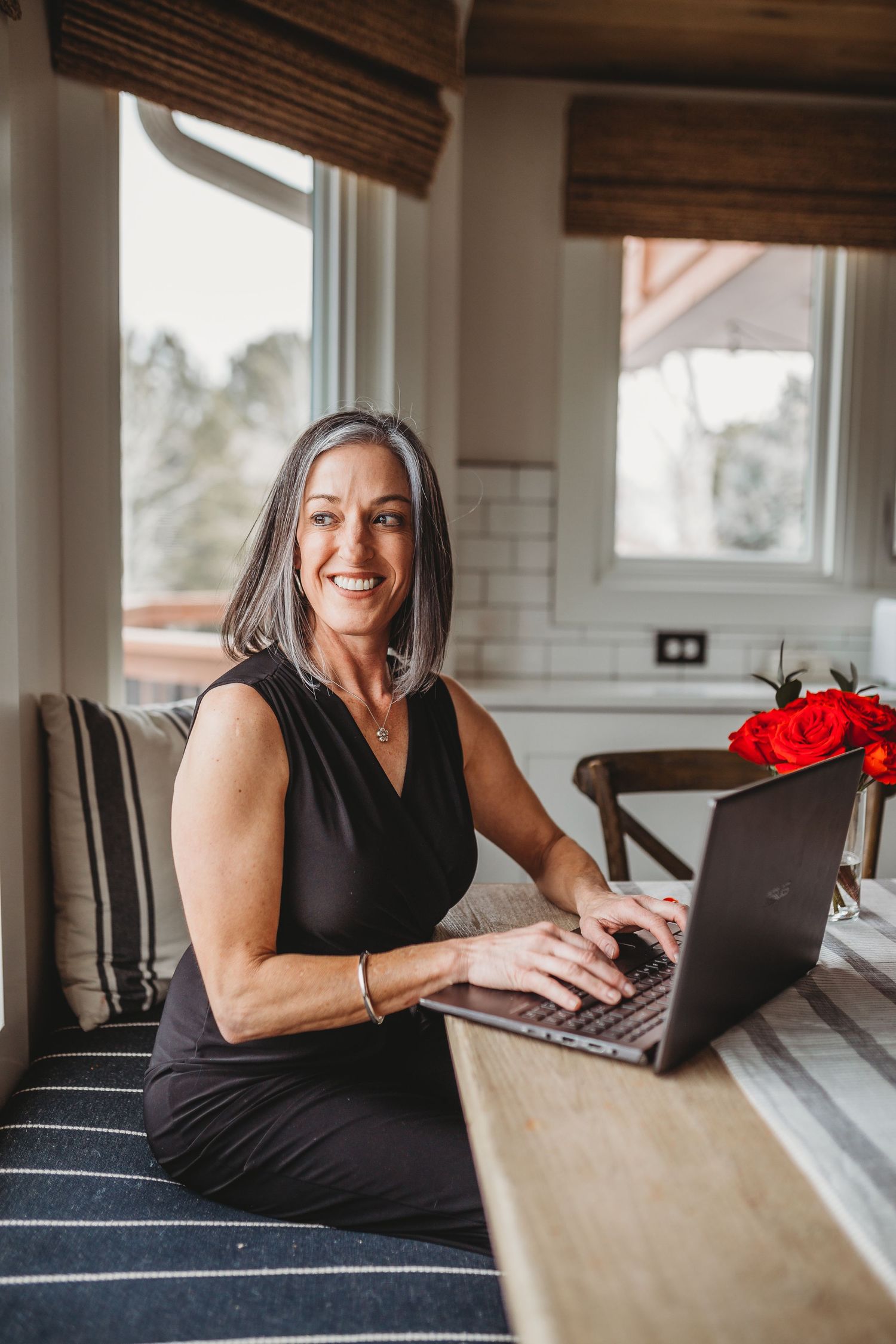 Person working on laptop at desk in bright modern home office with wood accents.